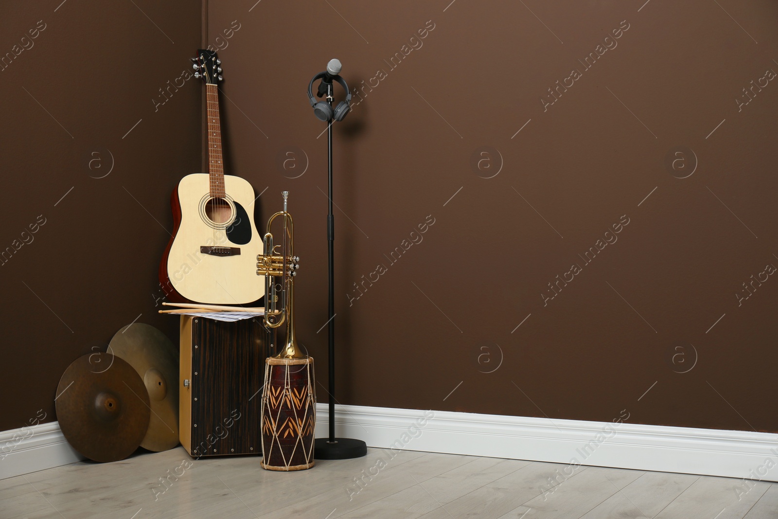 Photo of Set of different musical instruments and microphone near brown wall indoors, space for text