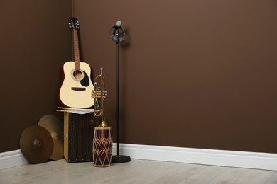 Set of different musical instruments and microphone near brown wall indoors, space for text