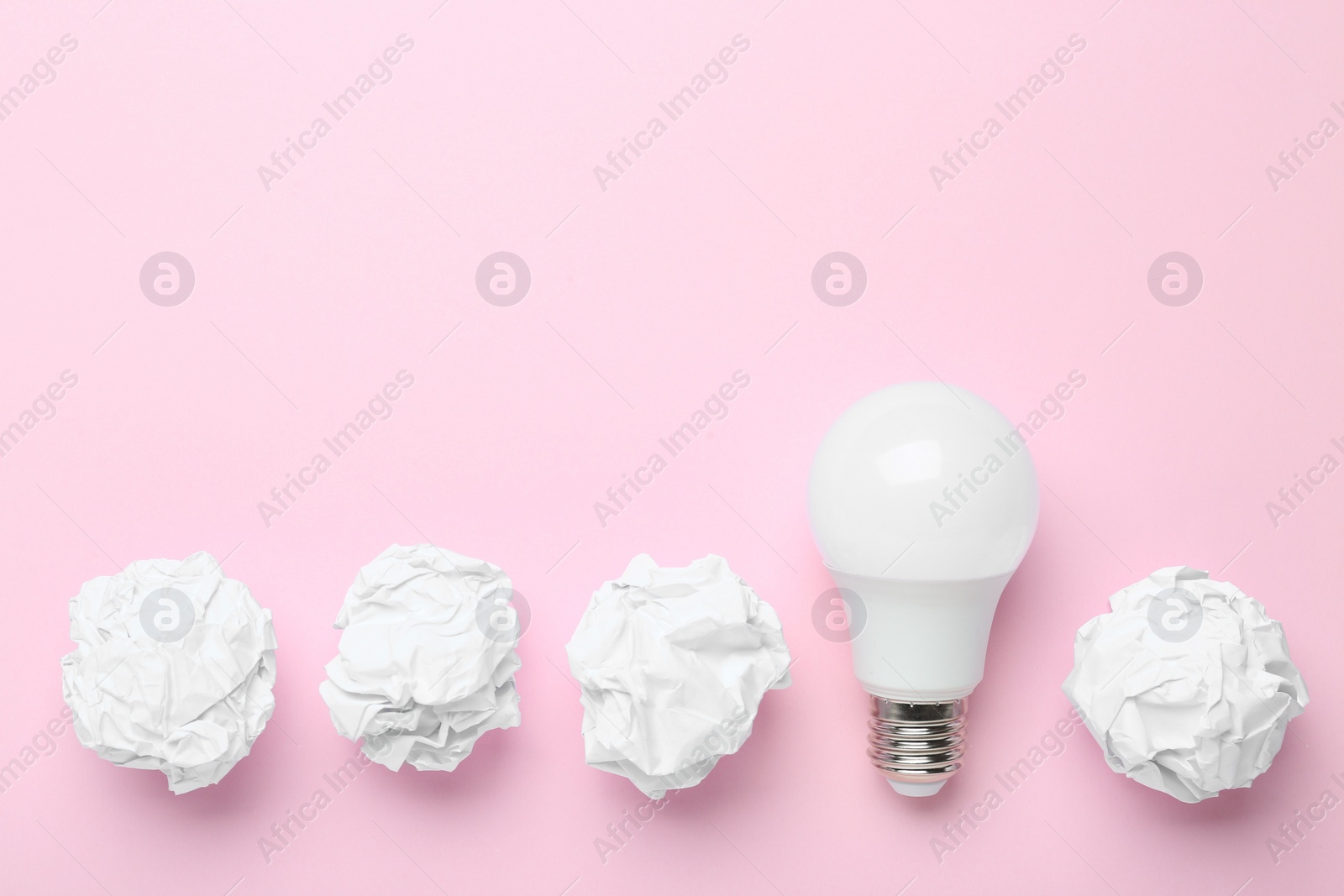 Photo of Creative flat lay composition with lightbulb and paper balls on pink background, space for text. Idea concept