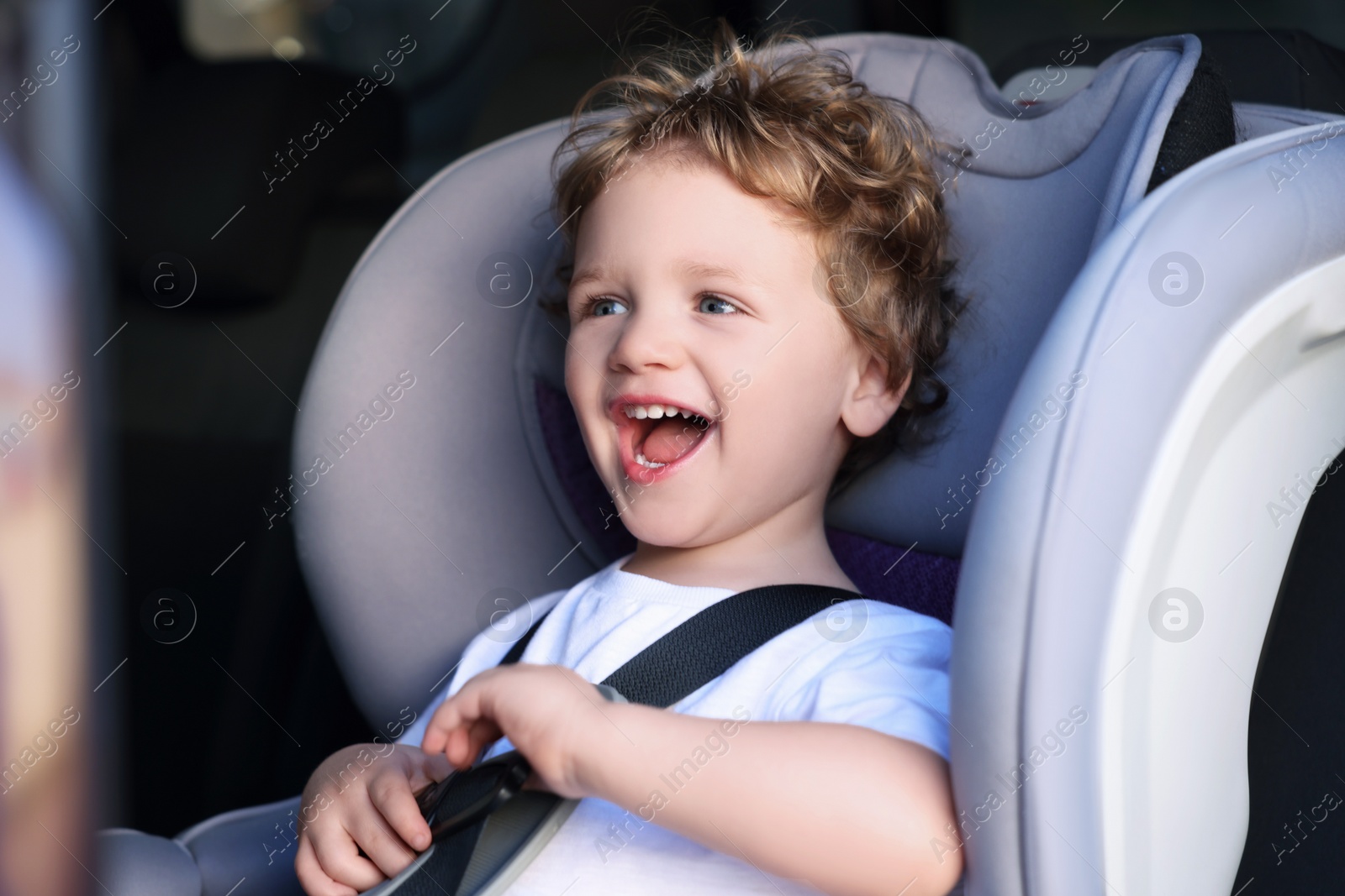 Photo of Cute little boy sitting in child safety seat inside car