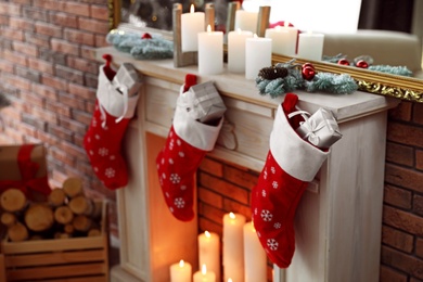 Decorative fireplace with Christmas stocking and gifts in stylish room interior