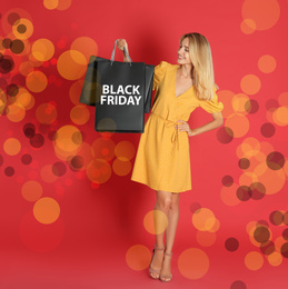 Black Friday sale. Happy young woman with shopping bags on red background, bokeh effect