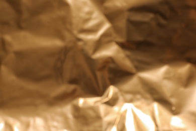 Blurred view of crumpled golden paper as background