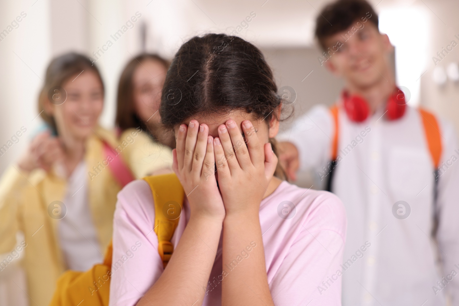 Photo of Teen problems. Lonely girl standing separately from other students at school