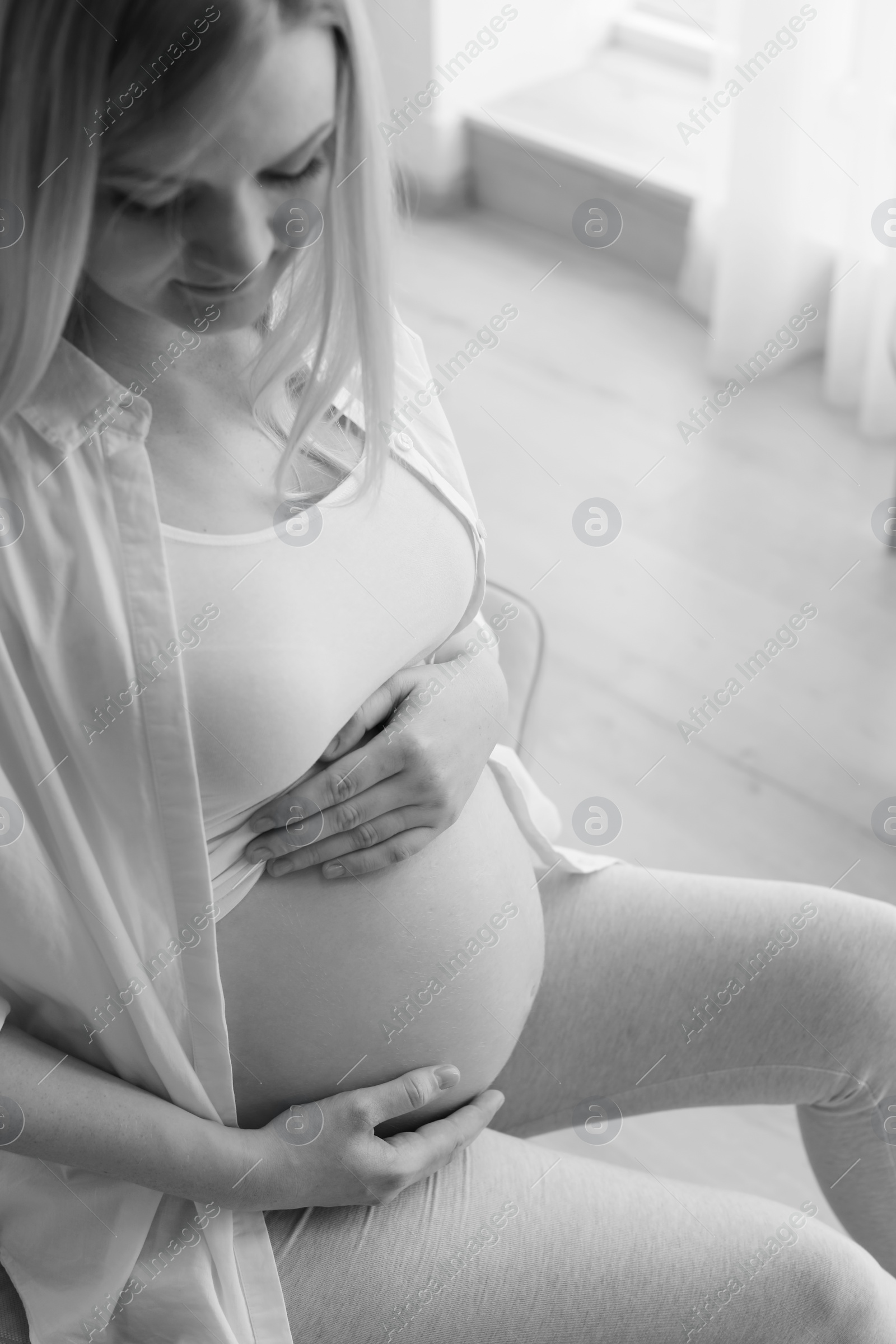 Photo of Beautiful pregnant woman sitting in room at home, black and white effect