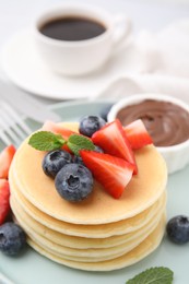 Photo of Delicious pancakes with strawberries, blueberries and mint on table, closeup