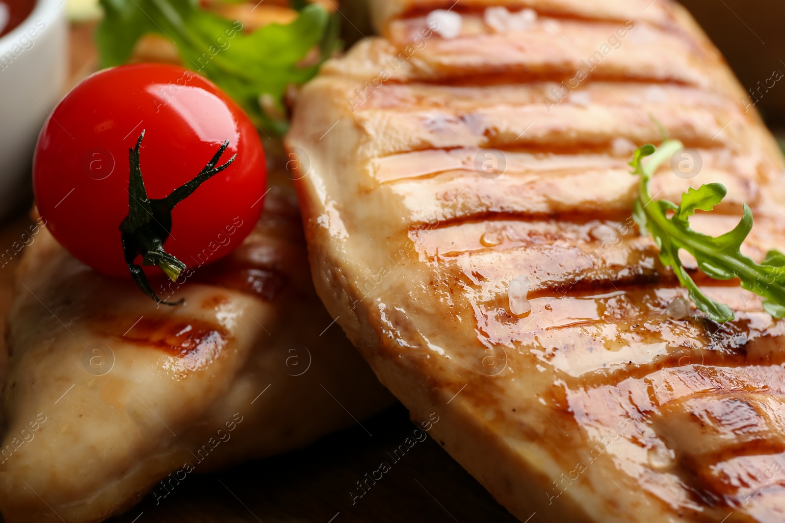 Photo of Tasty grilled chicken fillet with arugula and tomato, closeup