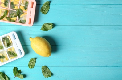 Flat lay composition with ice cube tray, mint and lemon on wooden background. Space for text