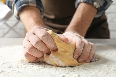 Photo of Young man kneading dough for pasta on table