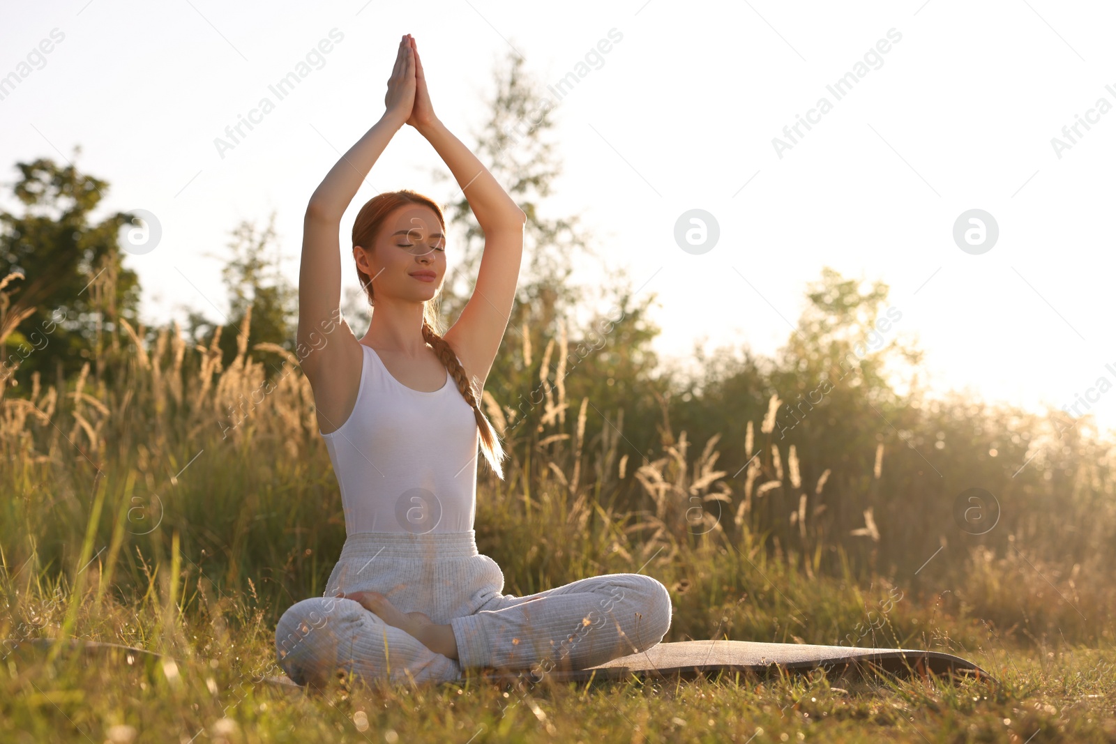 Photo of Beautiful woman practicing Padmasana on yoga mat outdoors, space for text. Lotus pose