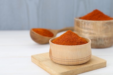 Photo of Bowls and spoon with aromatic paprika powder on white table. Space for text