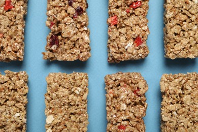 Photo of Different tasty granola bars on light blue background, flat lay