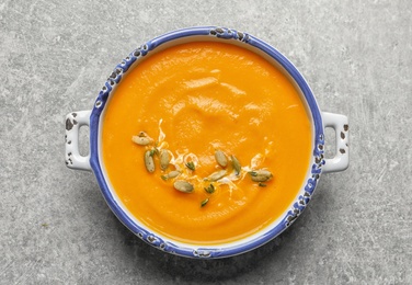 Bowl with tasty pumpkin soup on gray background, top view