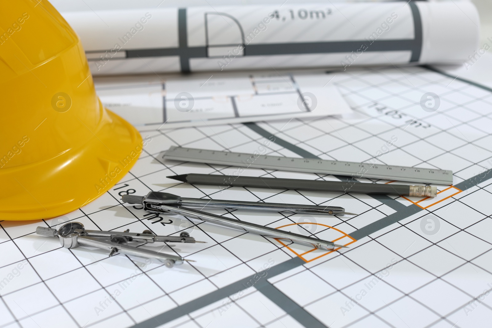 Photo of Construction drawings, safety hat and stationery, closeup view