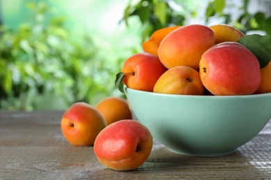 Photo of Many fresh ripe apricots on wooden table against blurred background