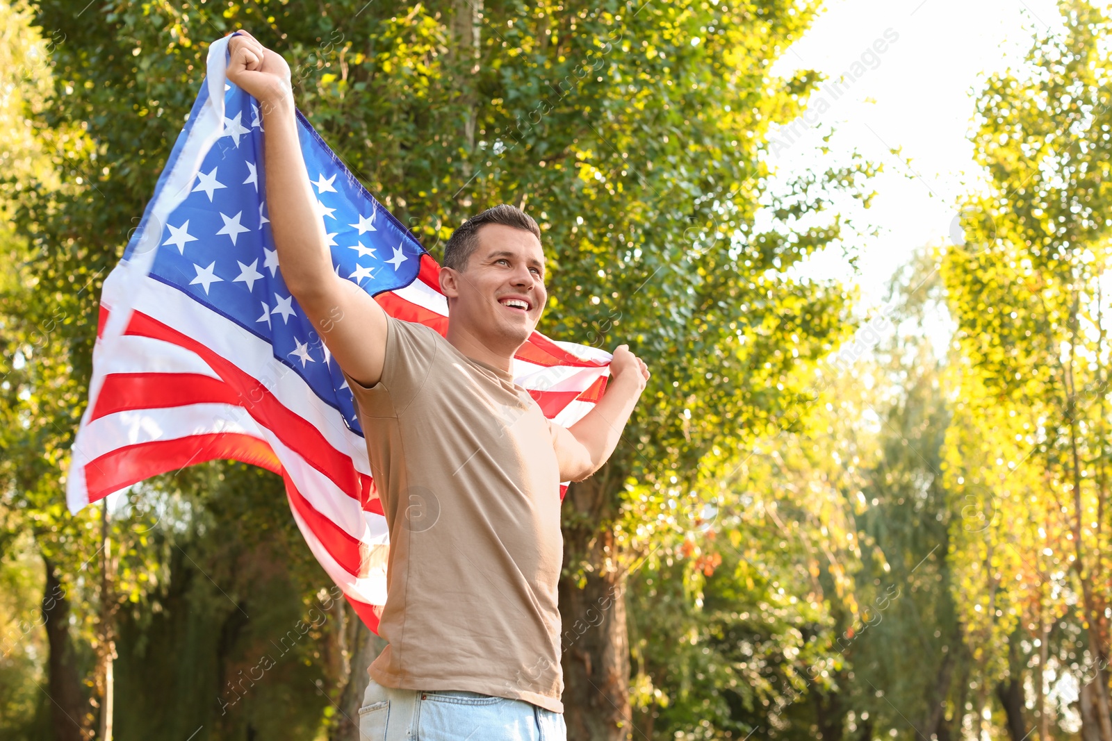 Photo of Man with American flag in park on sunny day