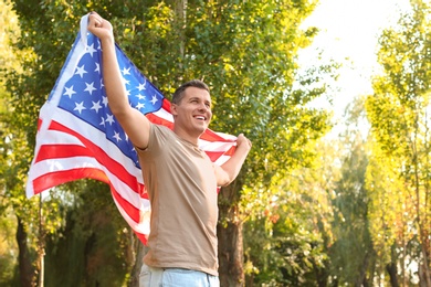 Man with American flag in park on sunny day