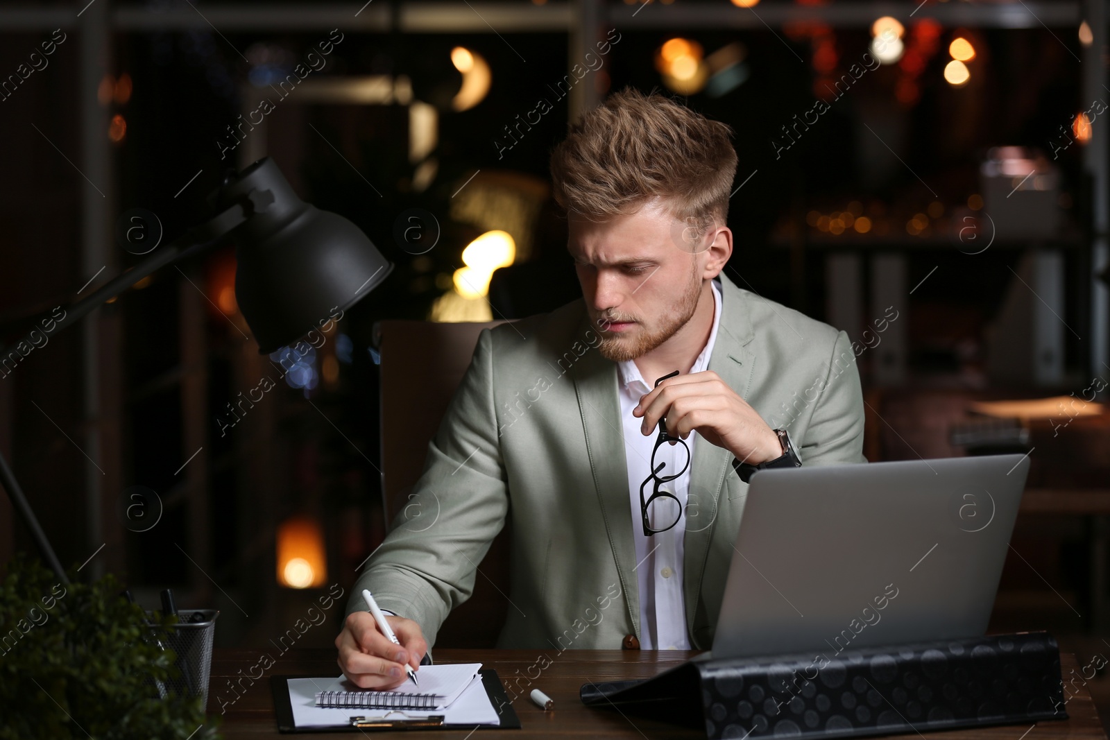 Photo of Young man working in office at night