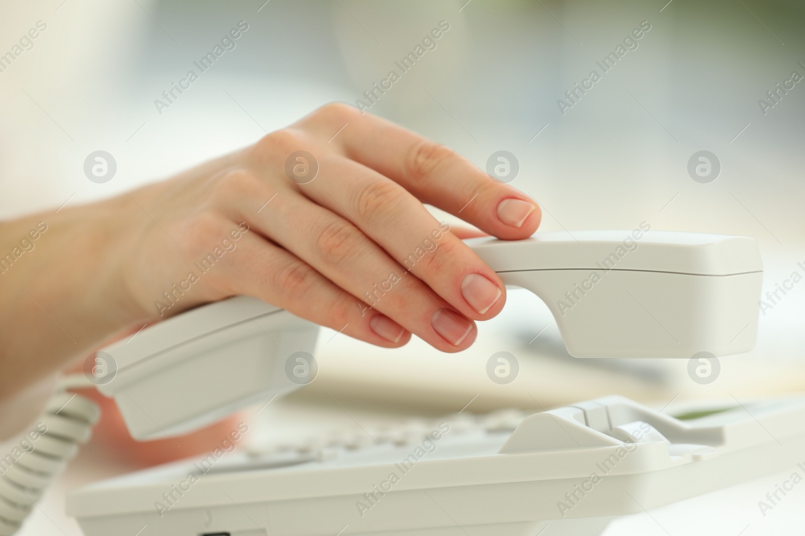 Photo of Assistant taking telephone handset on blurred background, closeup