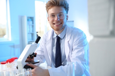 Photo of Male scientist with modern microscope in chemistry laboratory