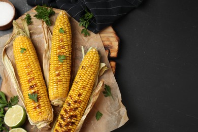 Tasty grilled corn on black table, flat lay. Space for text