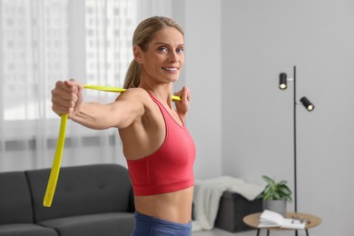 Athletic woman doing exercise with fitness elastic band at home