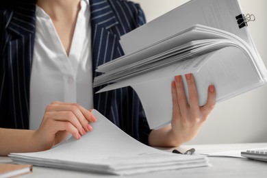 Photo of Woman reading documents at white table in office, closeup