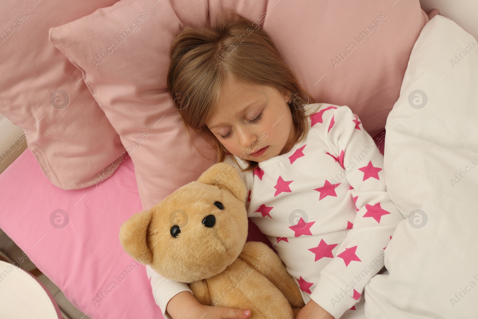 Photo of Little girl snoring while sleeping in bed, above view