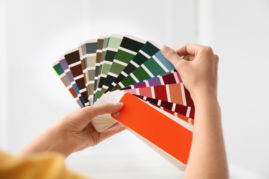 Photo of Female interior designer with color palette samples on light background, closeup