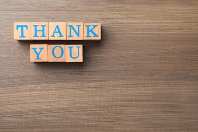 Photo of Phrase Thank You made of cubes with letters on wooden table, flat lay. Space for text