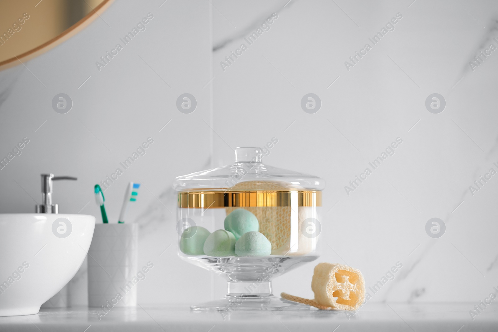 Photo of Jar with bath bombs and bath sponge on white countertop indoors