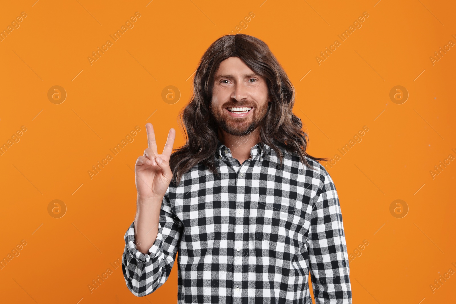 Photo of Hippie man showing V-sign on orange background