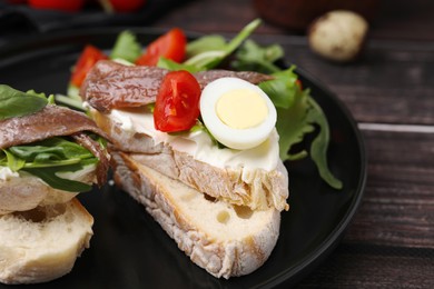 Photo of Delicious bruschettas with anchovies, cream cheese, arugula, eggs and tomatoes on wooden table, closeup