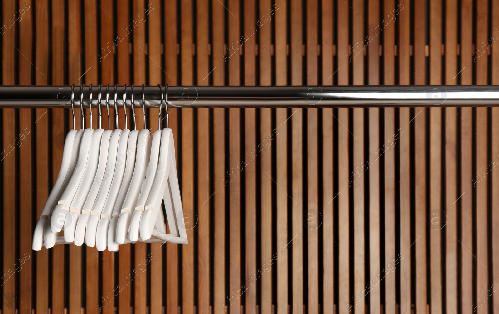 Photo of Empty hangers on rail against wooden background