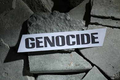 Photo of Paper with word Genocide on pieces of concrete, top view