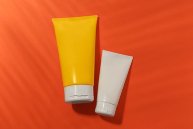 Photo of Sunscreens on coral background, flat lay. Sun protection care