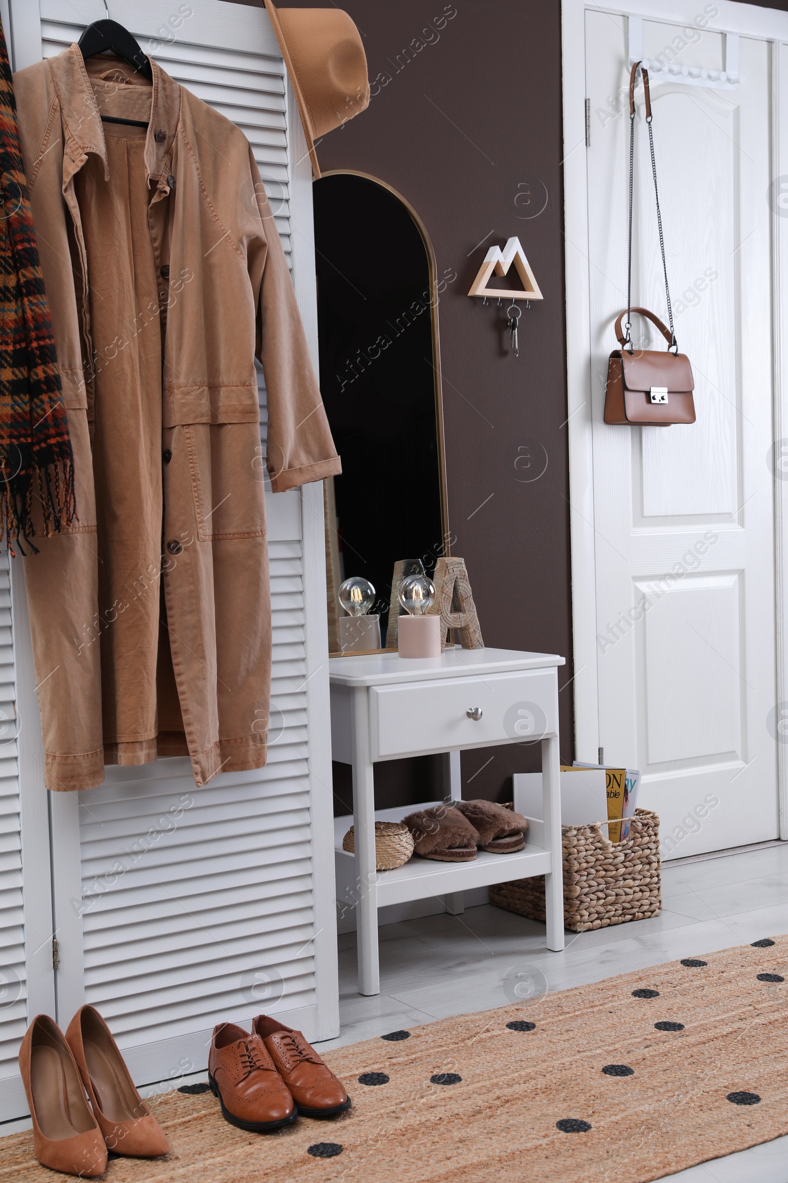 Photo of Modern hallway interior with stylish white furniture and wooden hanger for keys on brown wall