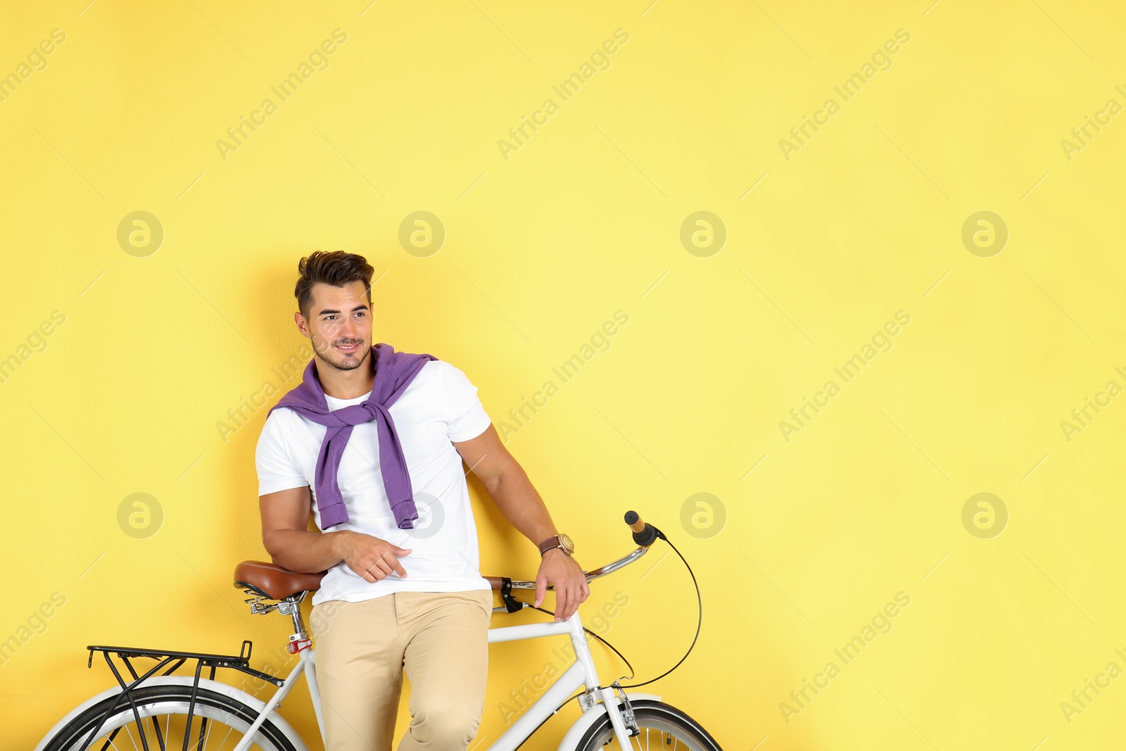 Photo of Handsome young hipster man with bicycle on yellow background