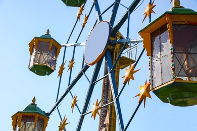 Photo of Beautiful large Ferris wheel against blue sky, low angle view