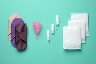 Photo of Different menstrual hygiene products on turquoise background, flat lay