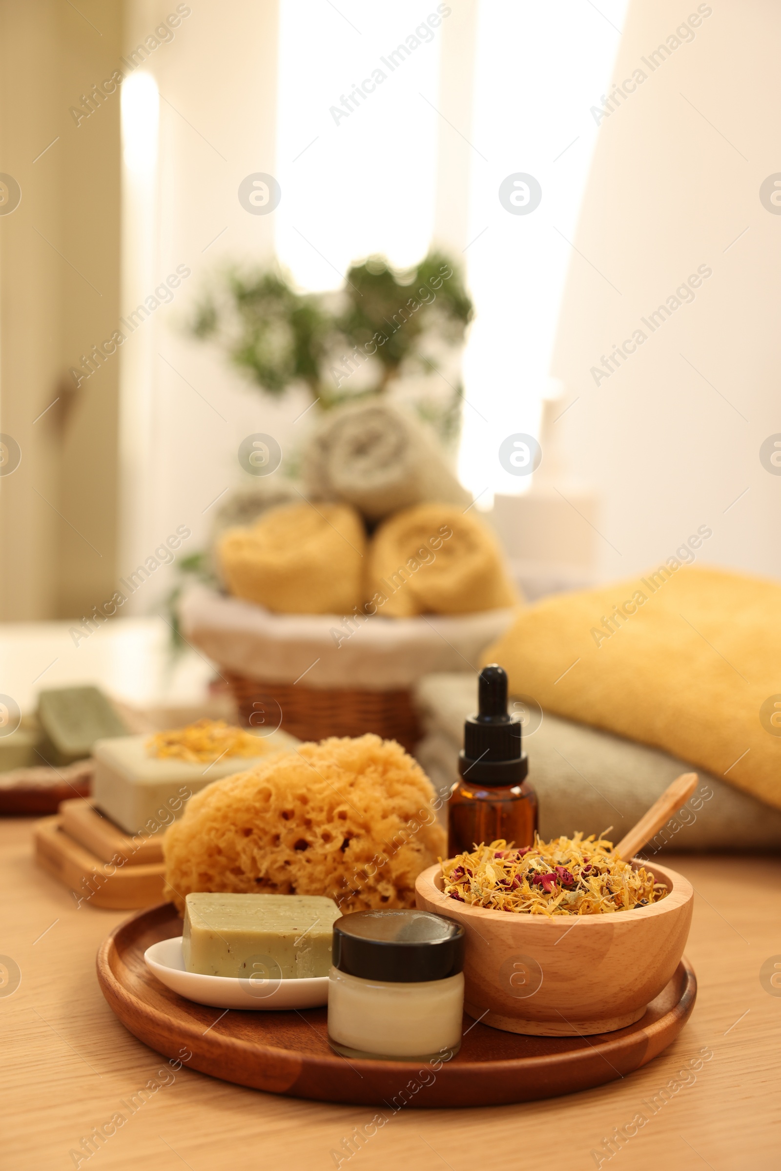 Photo of Dry flowers, loofah, soap bar, bottle of essential oil and jar with cream on wooden table indoors. Spa time