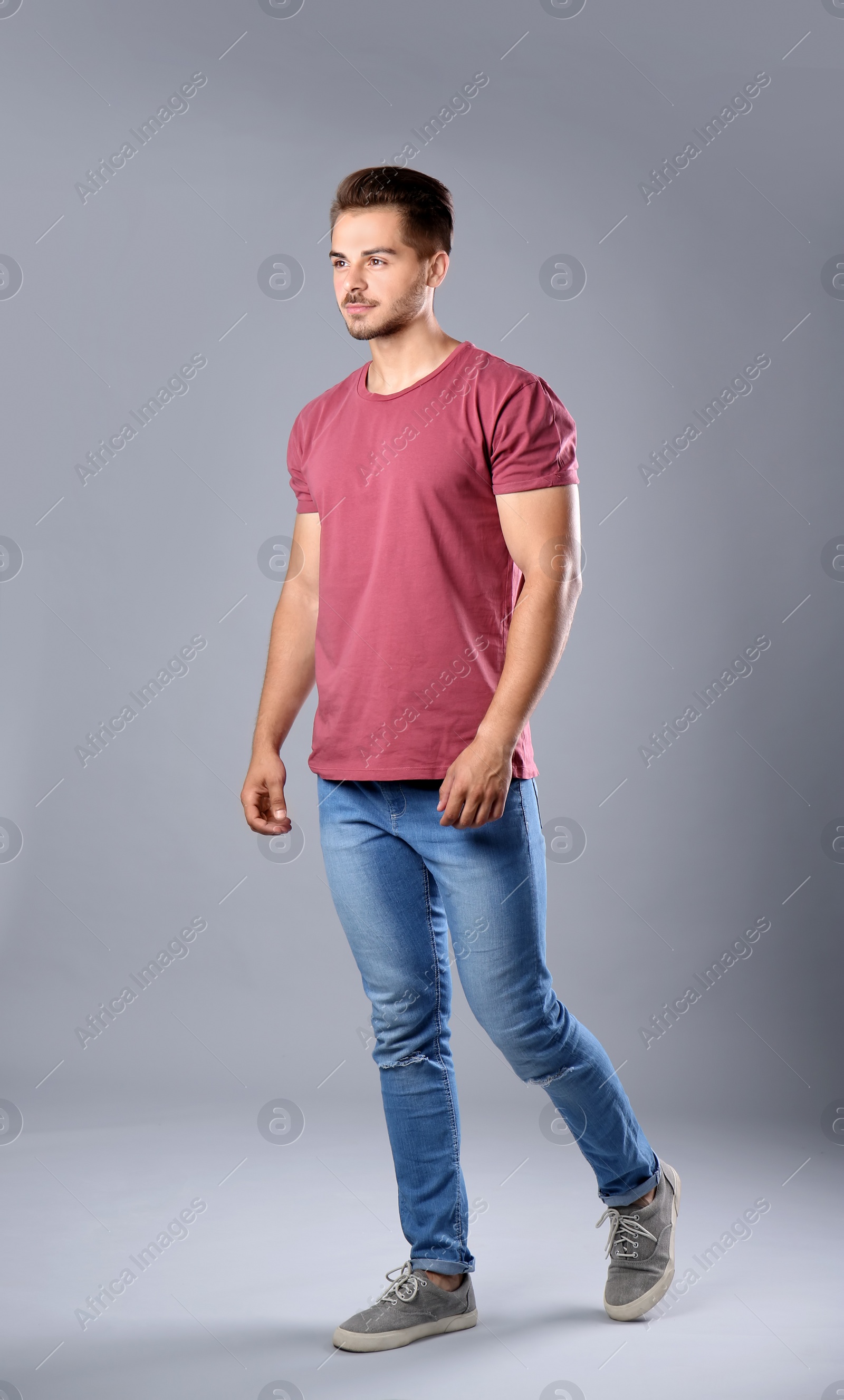 Photo of Young man in stylish jeans on grey background