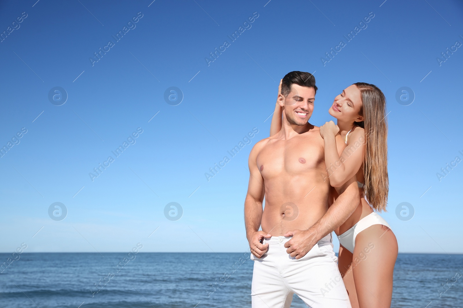 Photo of Woman in bikini and her boyfriend on beach, space for text. Happy couple