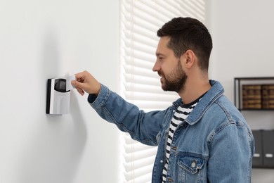 Photo of Home security system. Man using key card indoors