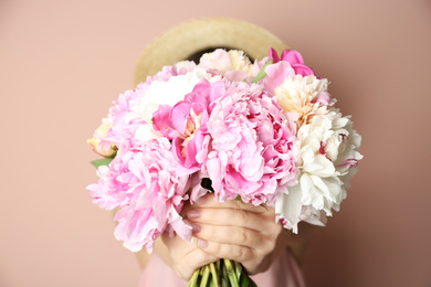 Photo of Woman with bouquet of beautiful peonies on beige background, closeup