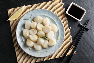 Photo of Raw scallops with lemon, rosemary and soy sauce on dark textured table, flat lay