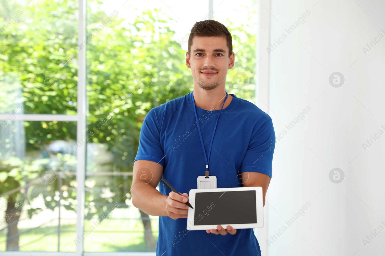 Photo of Young courier with tablet near window indoors