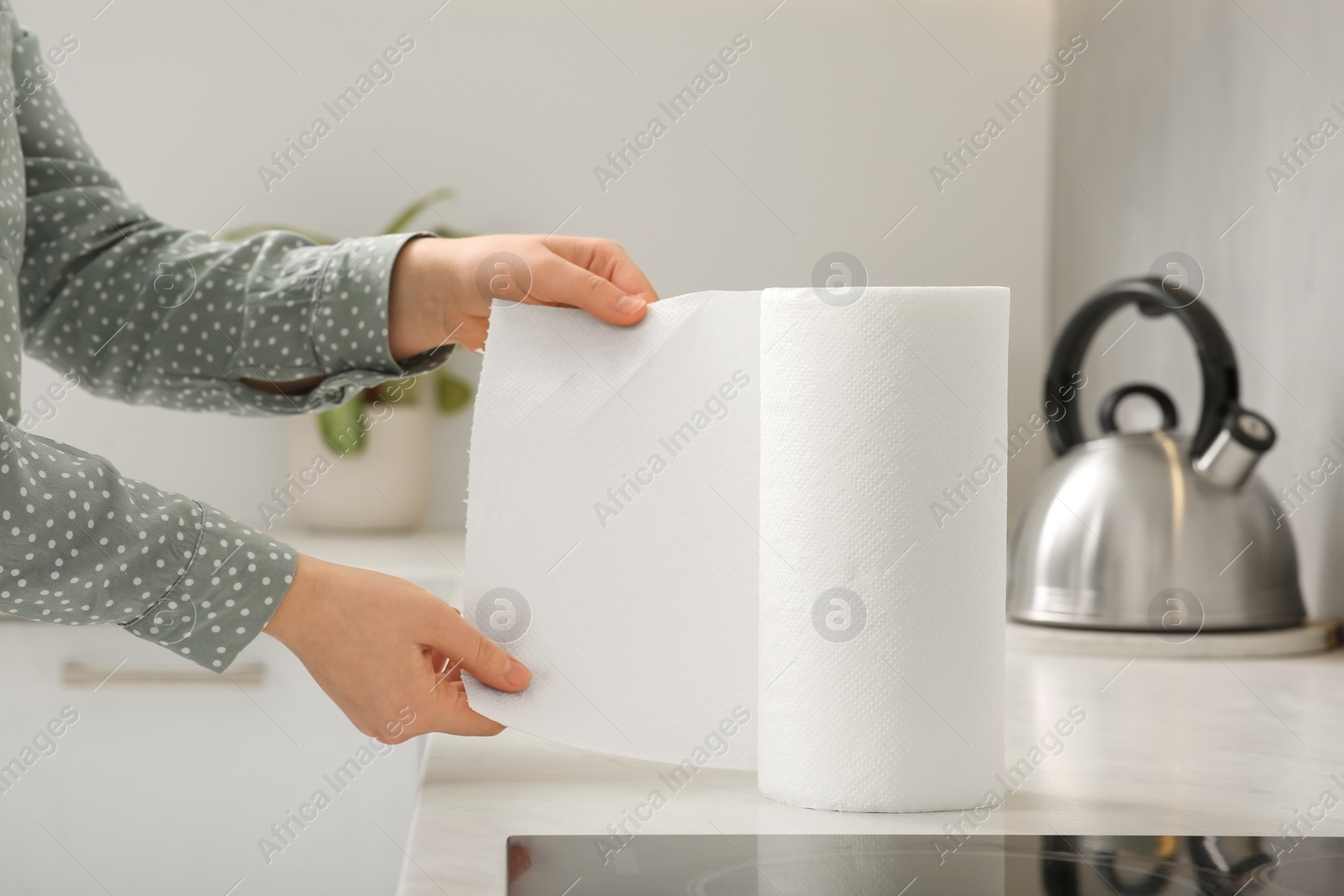 Photo of Woman tearing paper towels in kitchen, closeup