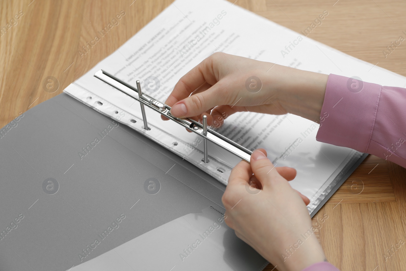 Photo of Woman fixing folder with punched pockets at wooden table, closeup