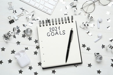 Inscription 2021 Goals in notebook, new year aims. Objects on white wooden table, flat lay